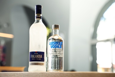 Photo of MYKOLAIV, UKRAINE - SEPTEMBER 23, 2019: Bottles of Finlandia and Absolut vodka on wooden counter in bar