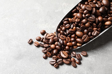 Photo of Scoop with roasted coffee beans on grey background, closeup