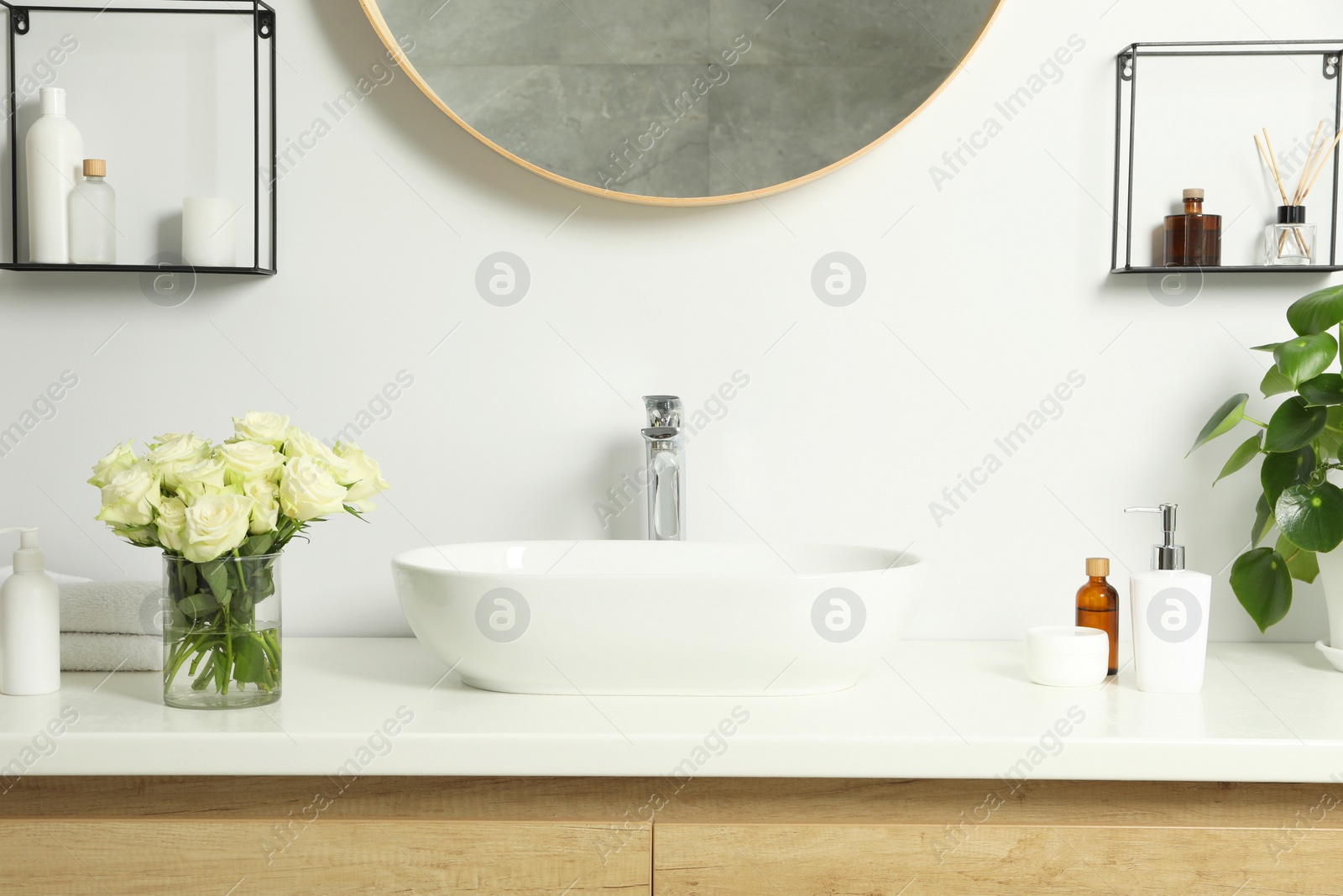 Photo of Beautiful roses and bath accessories near sink in bathroom