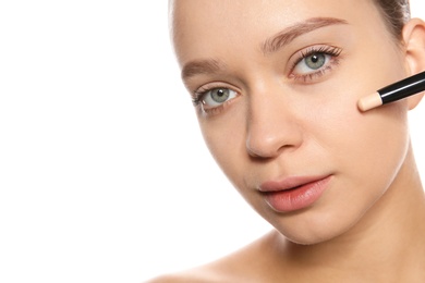 Photo of Young woman applying foundation on her face against white background