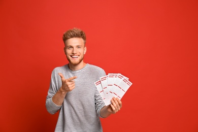 Photo of Portrait of happy young man with lottery tickets on red background