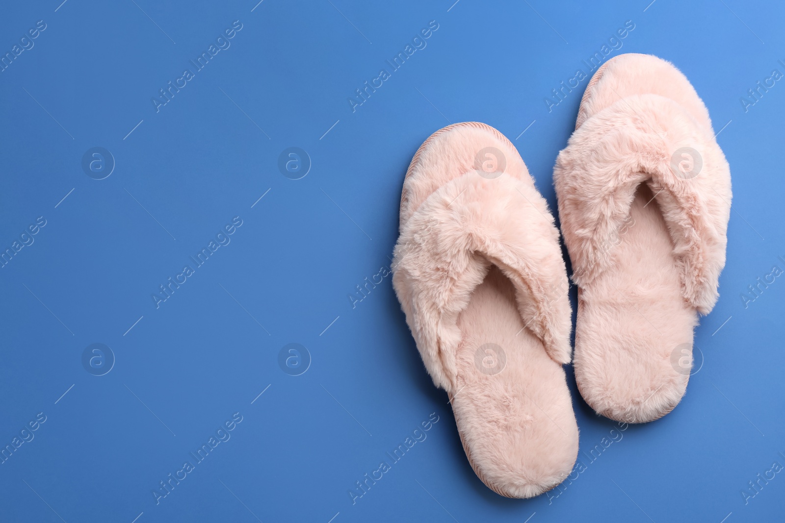 Photo of Pair of stylish soft slippers on blue background, flat lay. Space for text