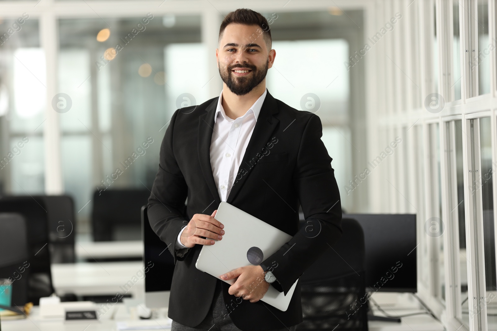 Photo of Portrait of smiling man with laptop in office. Lawyer, businessman, accountant or manager