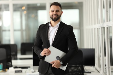 Portrait of smiling man with laptop in office. Lawyer, businessman, accountant or manager