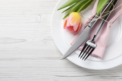Photo of Stylish table setting with cutlery and tulip on white wooden background, top view. Space for text