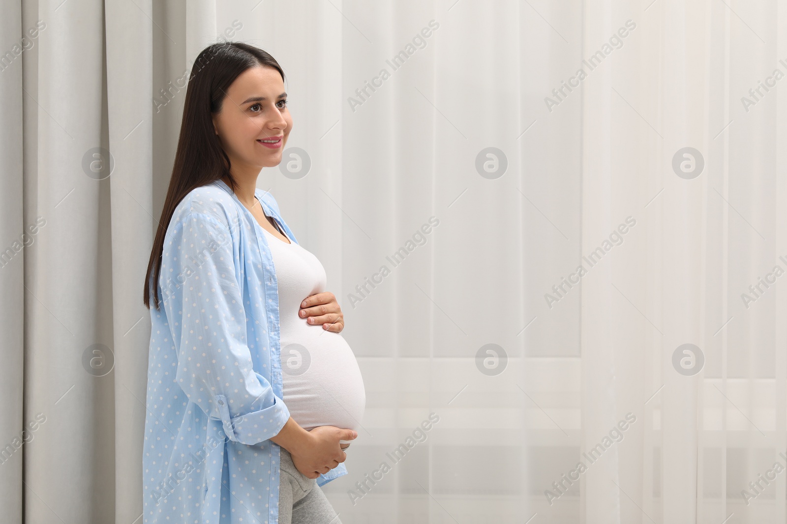 Photo of Beautiful pregnant woman indoors, space for text