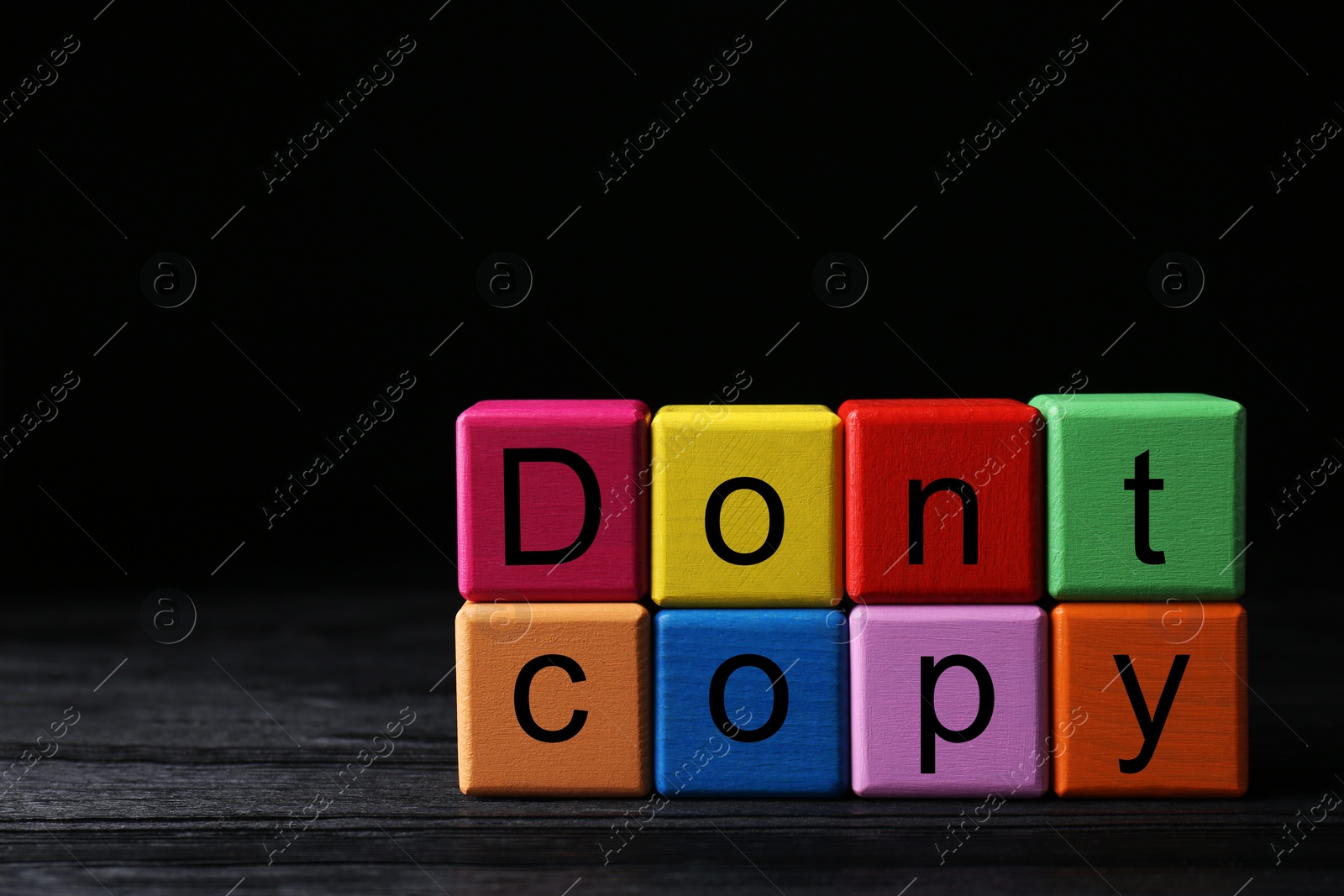 Photo of Colorful cubes with words Don't Copy on black wooden table, space for text. Plagiarism concept