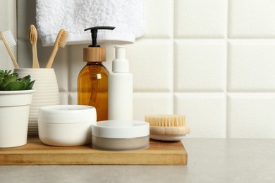 Photo of Different bath accessories and personal care products on gray table near white tiled wall, space for text