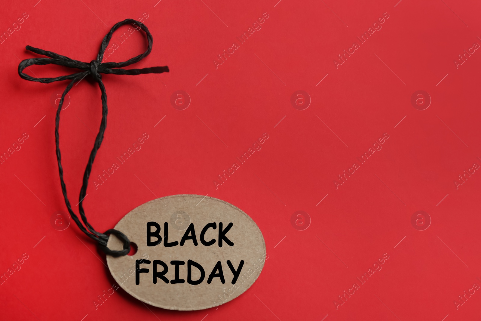 Photo of Top view of tag with words BLACK FRIDAY on red background, space for text