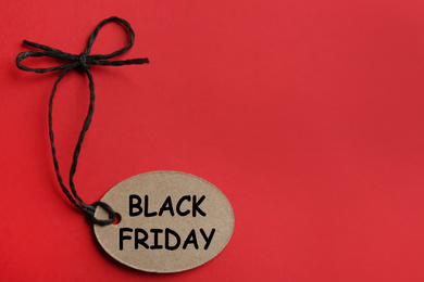 Photo of Top view of tag with words BLACK FRIDAY on red background, space for text