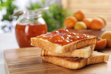 Photo of Bread with tasty apricot jam on wooden board