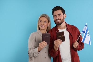 Photo of Immigration. Happy couple with passports and flag of Israel on light blue background, space for text