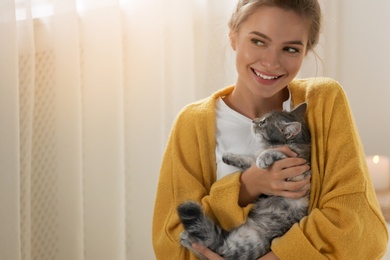 Photo of Young woman with cute cat at home. Cozy winter