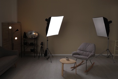 Photo of Interior of modern photo studio with rocking chair, table and professional equipment