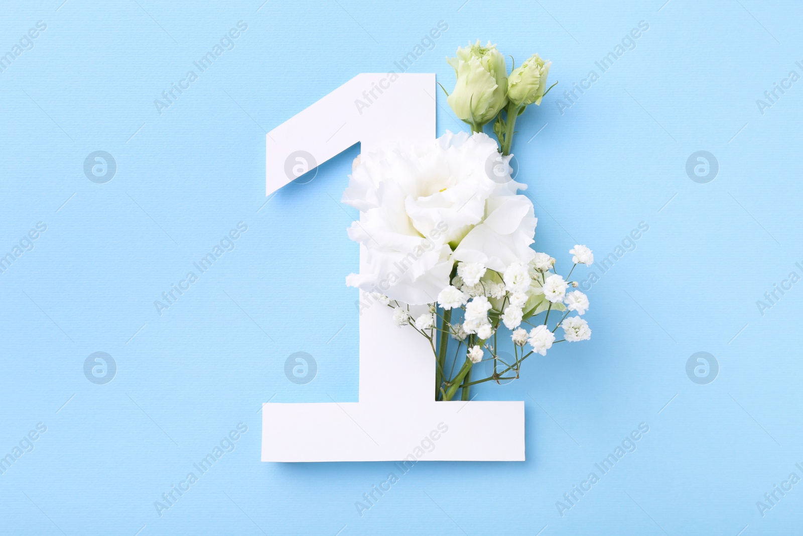 Photo of Paper number 1 and beautiful flowers on light blue background, top view