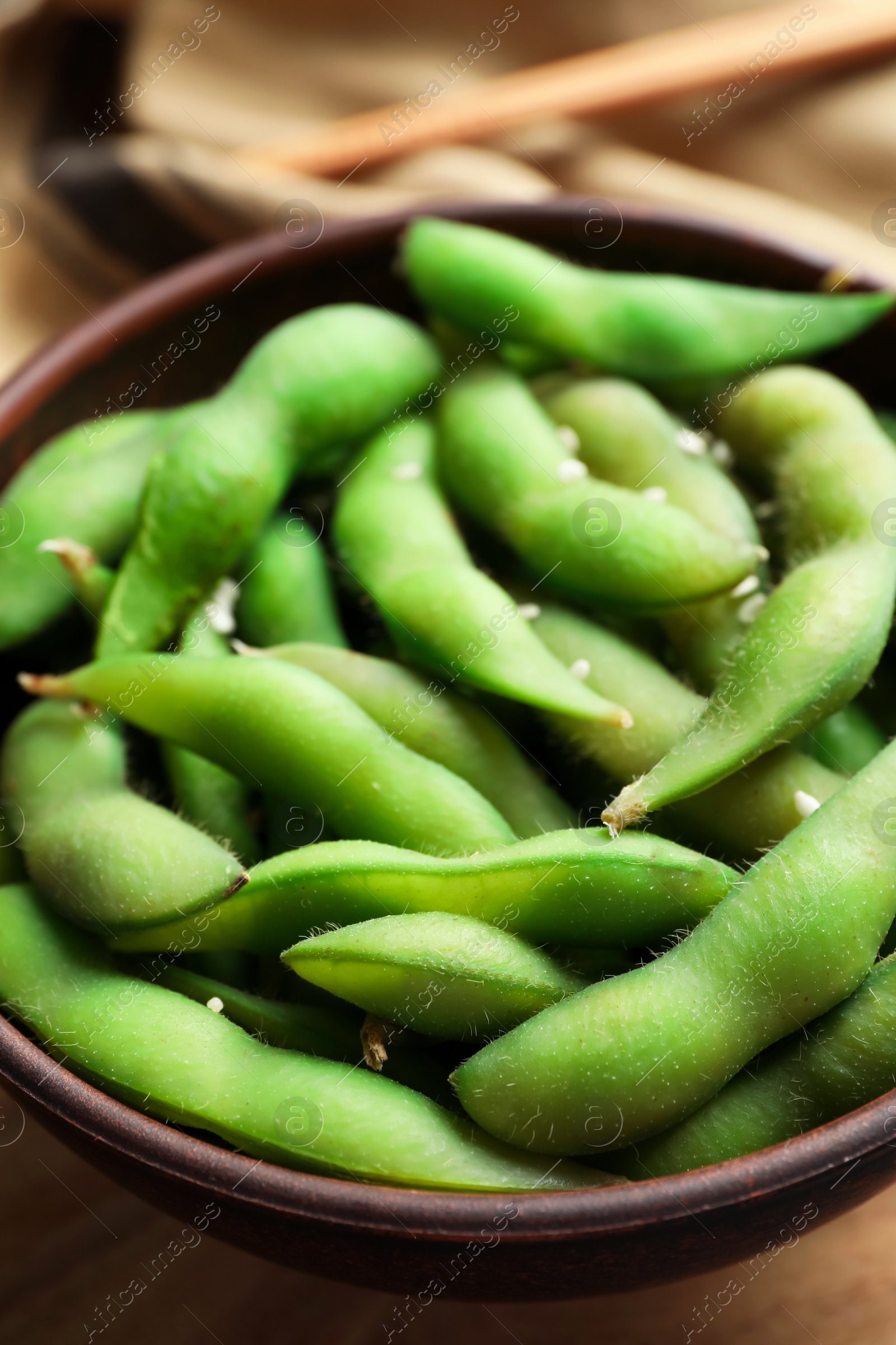 Photo of Bowl with green edamame beans in pods on table, closeup