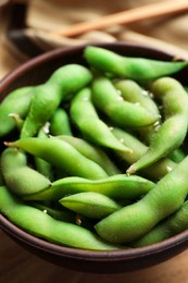 Photo of Bowl with green edamame beans in pods on table, closeup