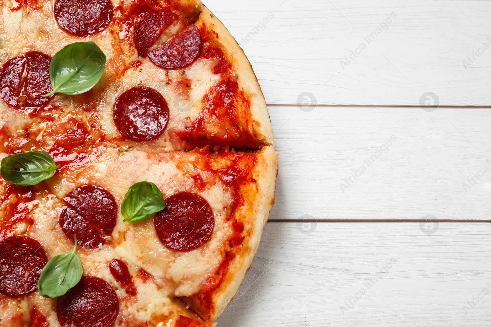 Photo of Hot delicious pepperoni pizza on white wooden table, top view. Space for text