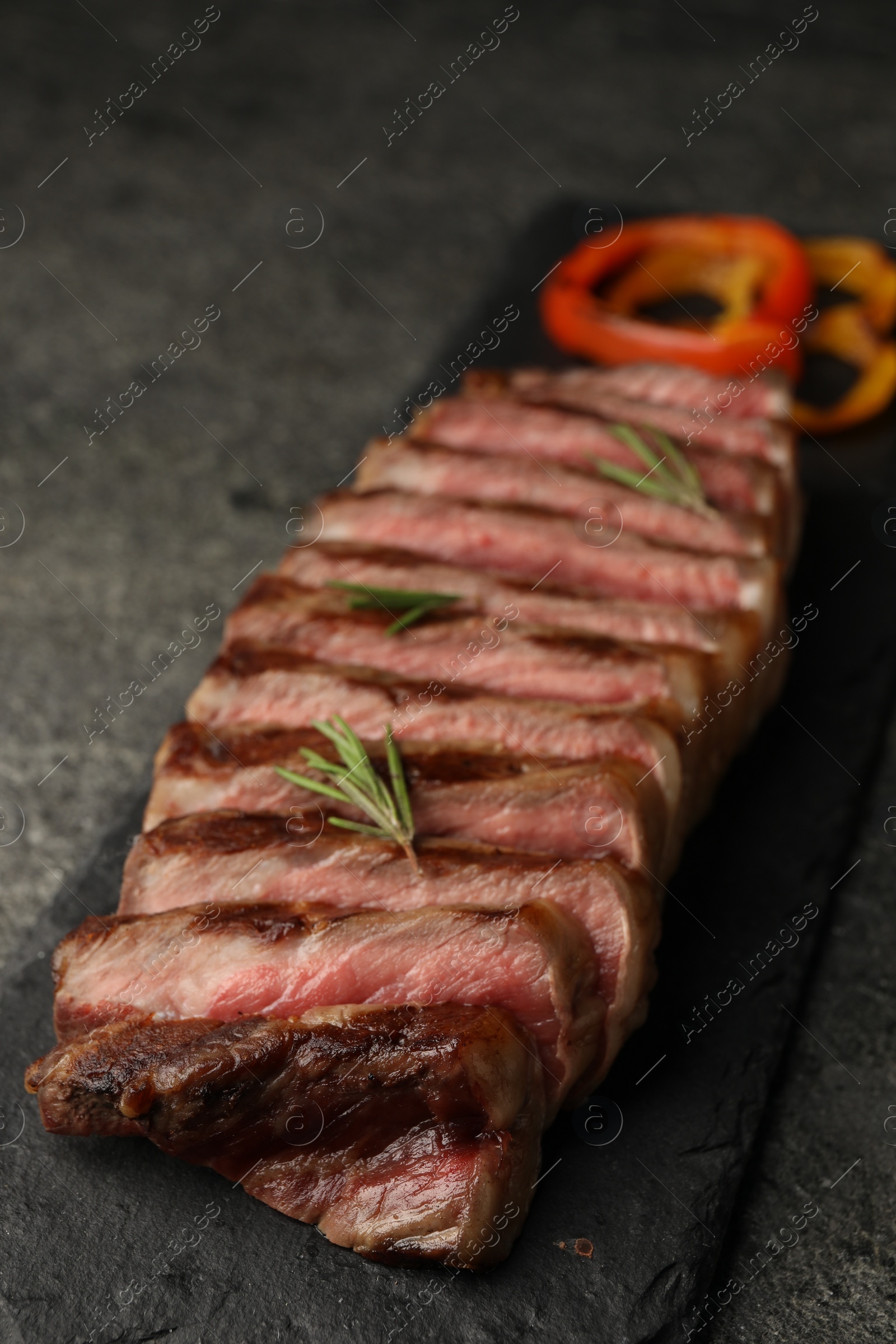 Photo of Delicious grilled beef steak with rosemary on dark gray table