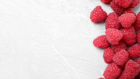 Photo of Delicious fresh ripe raspberries on light marble table, flat lay. Space for text