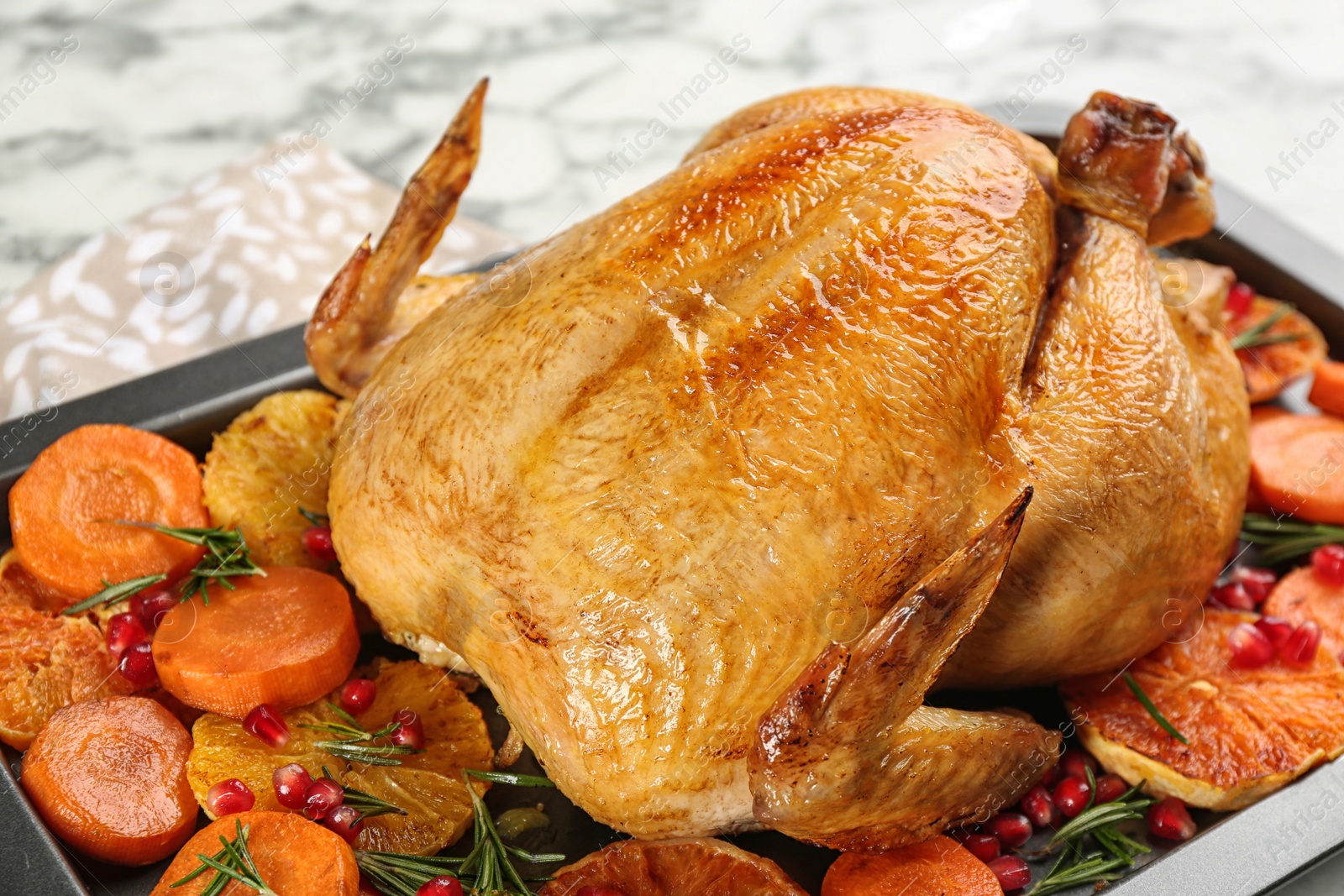 Photo of Roasted chicken with oranges, pomegranate and vegetables in baking pan, closeup