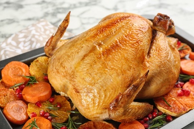 Photo of Roasted chicken with oranges, pomegranate and vegetables in baking pan, closeup