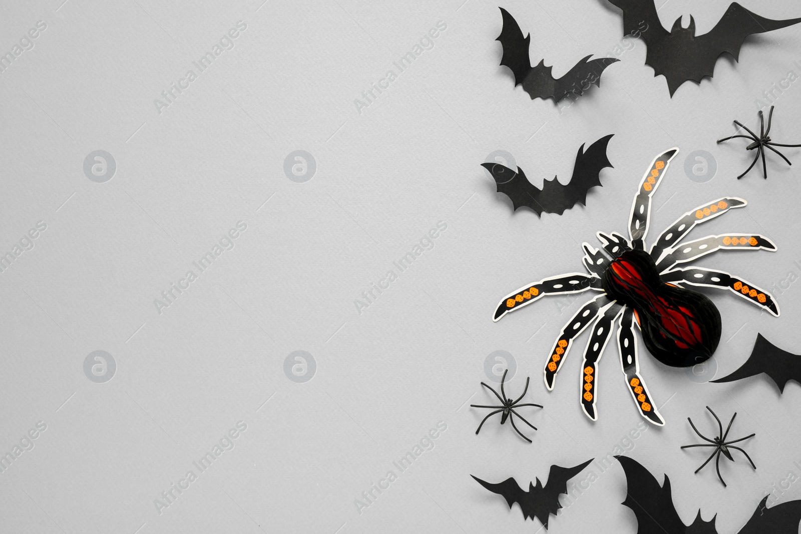 Photo of Flat lay composition with paper bats and spiders on light grey background, space for text. Halloween decor