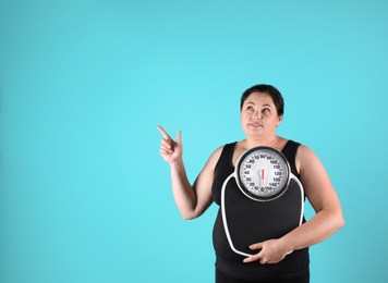 Overweight woman in sportswear with scales on color background