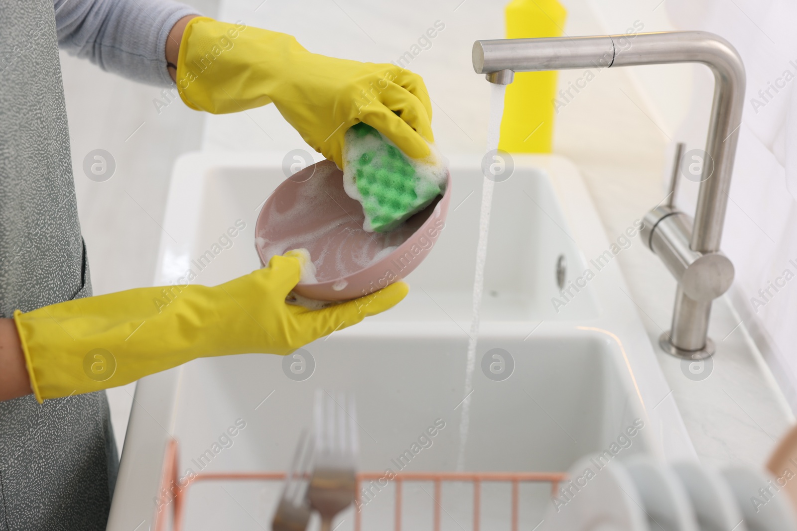 Photo of Woman washing plate above sink in modern kitchen, closeup