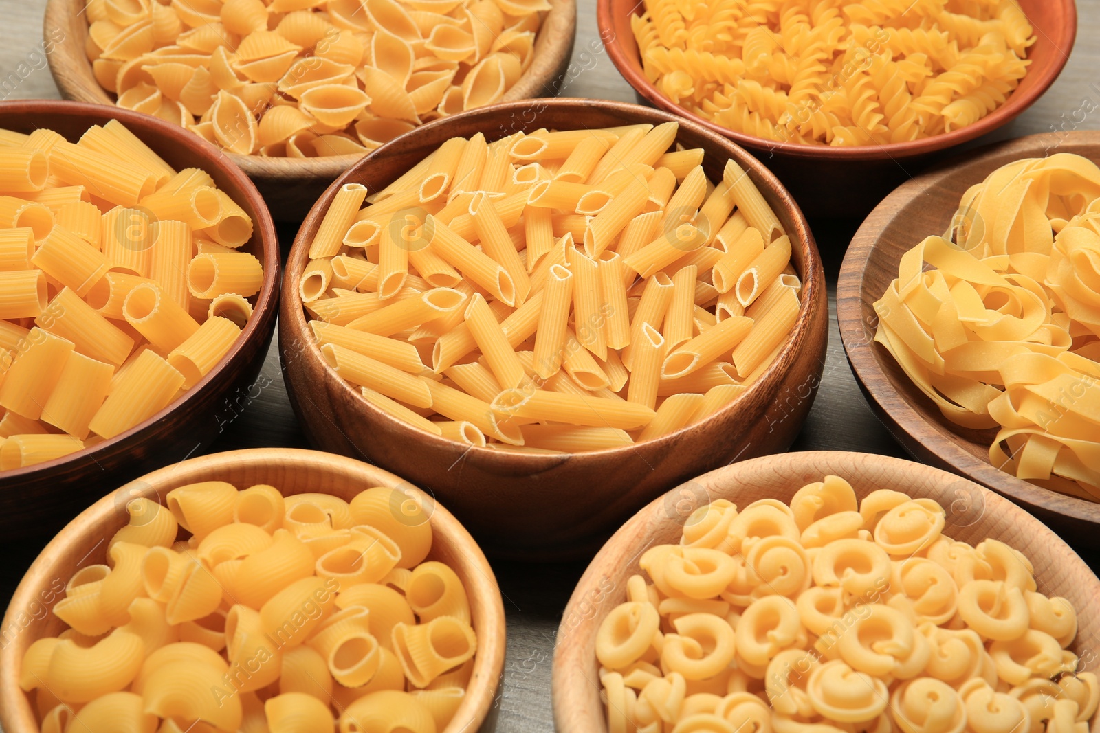 Photo of Different types of pasta in bowls on table, closeup