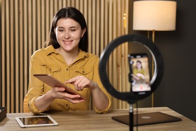 Photo of Smiling technology blogger recording video review about tablets at home