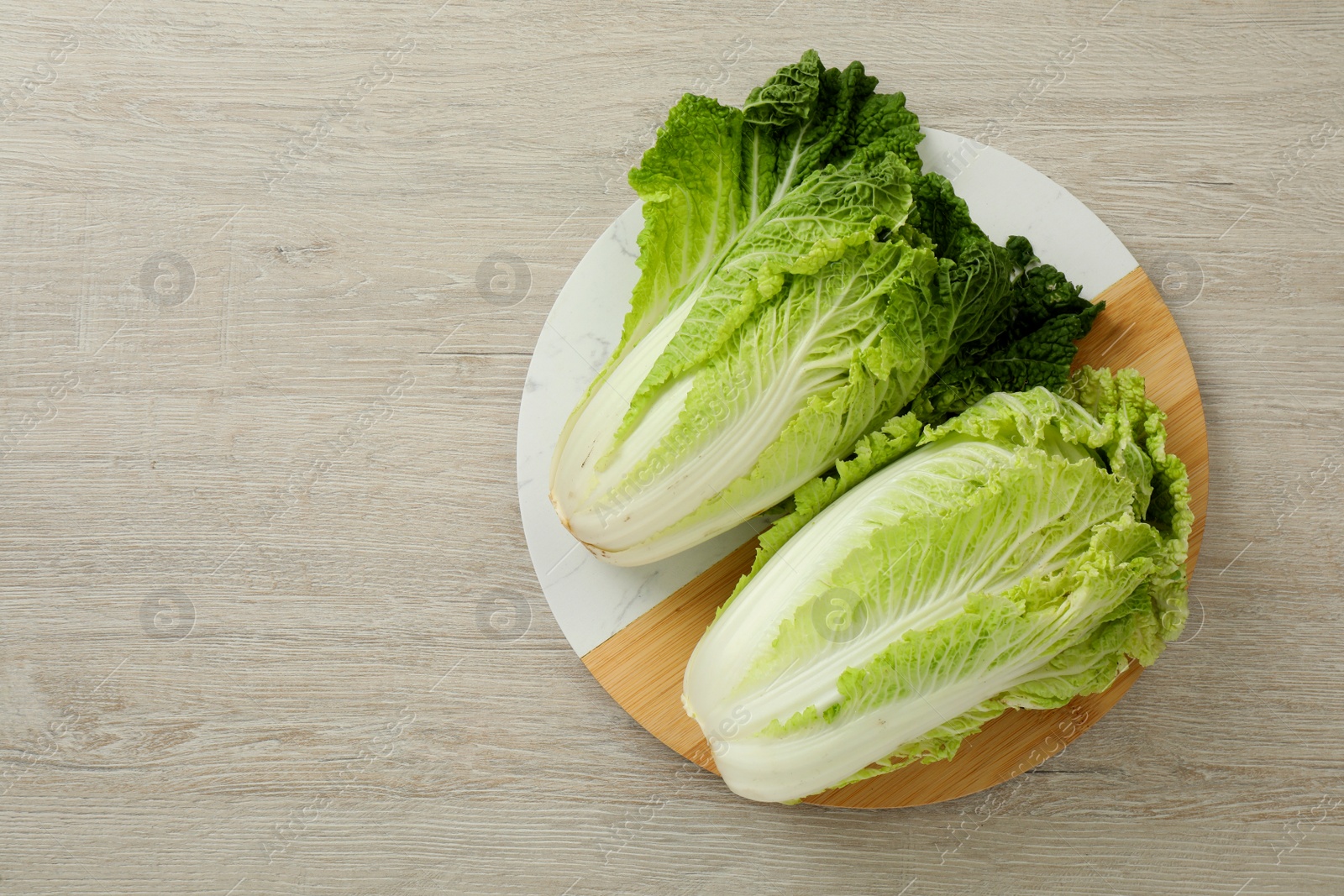 Photo of Fresh ripe Chinese cabbages on white wooden table, top view. Space for text