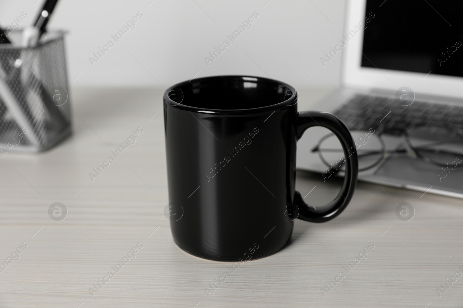Black ceramic mug, laptop and glasses on white wooden table at workspace Photo of Black ceramic mug, laptop and glasses on white wooden table at workspace
