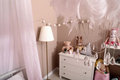 Photo of Beautiful decorative cloud with crystals hanging over bed in child's room. Interior design