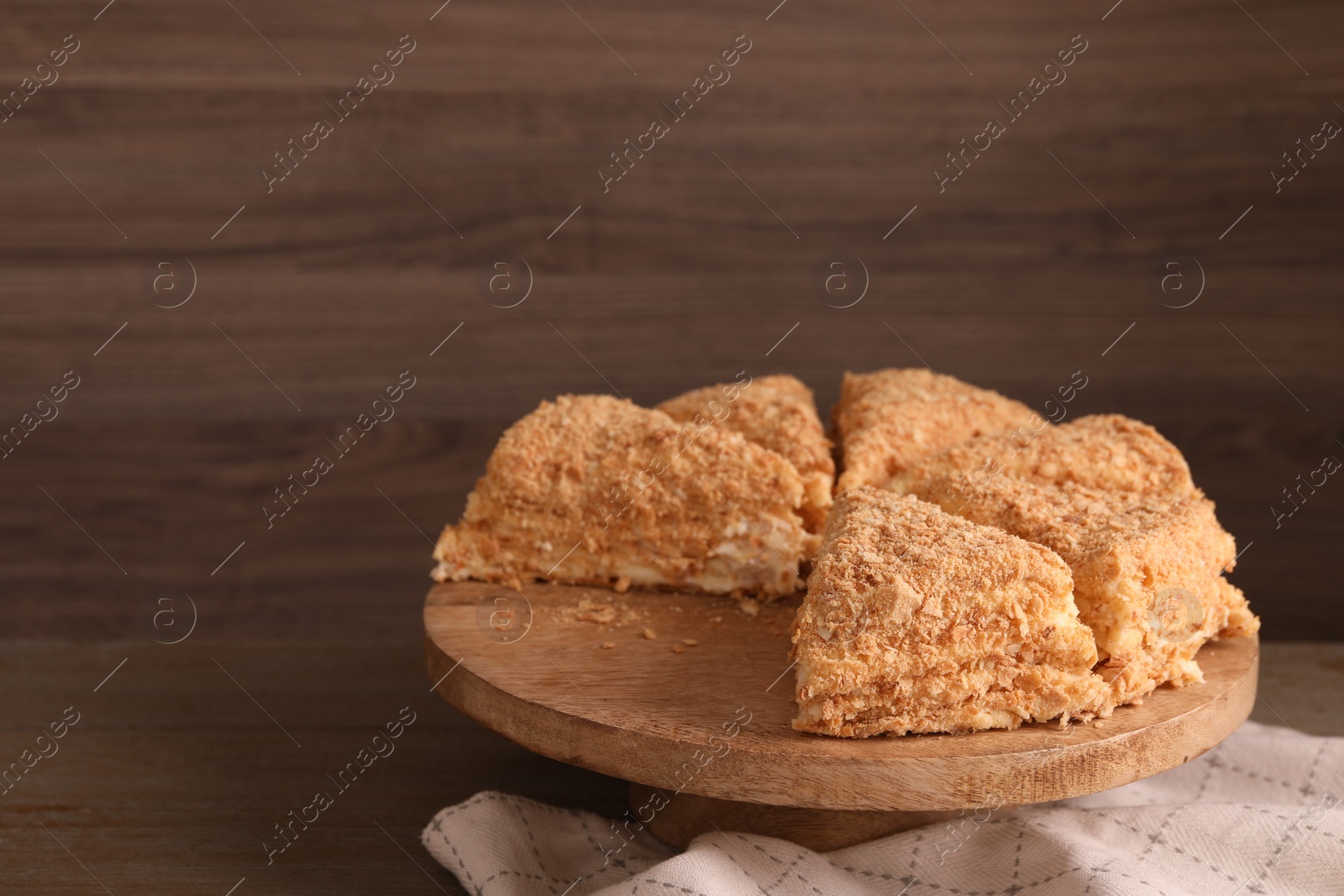 Photo of Pieces of delicious Napoleon cake on table, closeup. Space for text