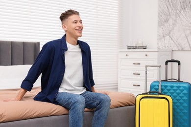 Smiling guest relaxing on bed in stylish hotel room