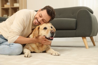 Photo of Man hugging his cute Labrador Retriever at home. Space for text