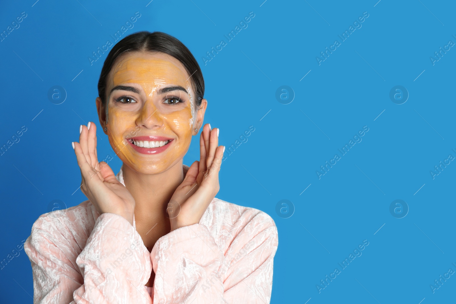 Photo of Young woman with cleansing mask on her face against color background, space for text. Skin care