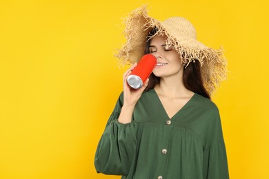 Beautiful happy woman drinking from beverage can on yellow background. Space for text