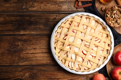 Photo of Raw traditional English apple pie in baking dish on wooden table, flat lay. Space for text