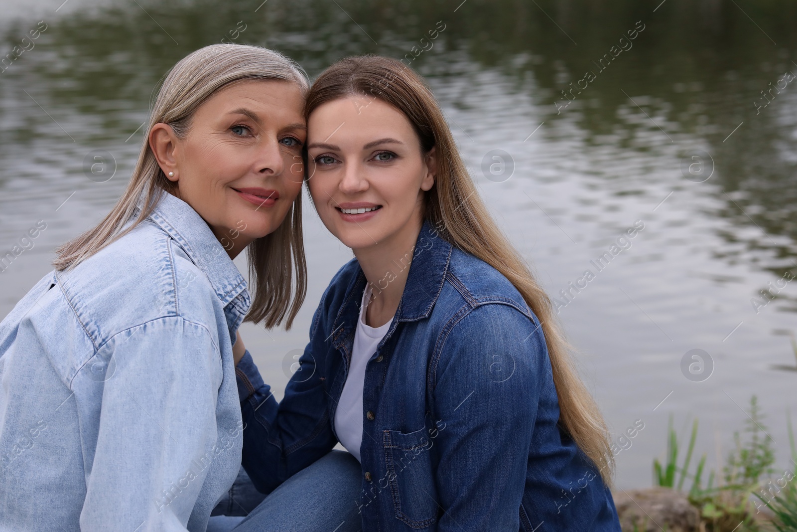 Photo of Happy mature mother and her daughter near pond