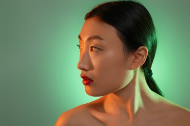 Photo of Portrait of beautiful young Asian woman on green background, space for text