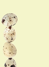 Image of Stacked speckled quail eggs on light beige background. Space for text