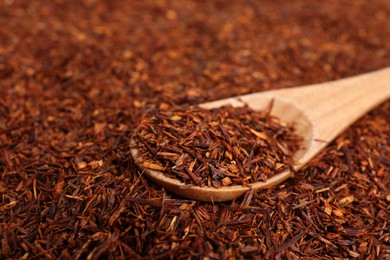 Photo of Heap of dry rooibos tea leaves with wooden spoon, closeup. Space for text