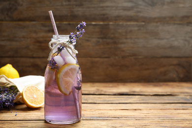 Photo of Fresh delicious lemonade with lavender on wooden table. Space for text