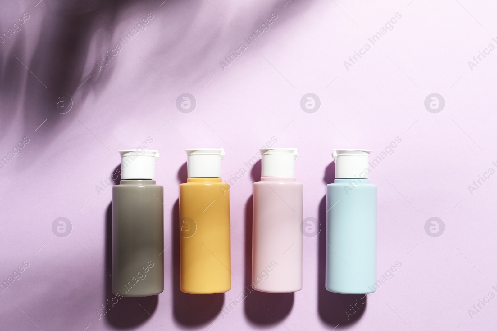 Photo of Cosmetic travel kit on violet background, top view. Space for text