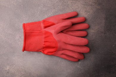 Pair of red gardening gloves on brown textured table, top view