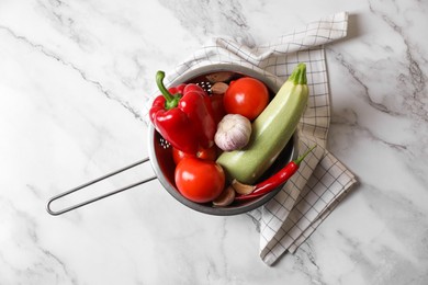 Photo of Fresh vegetables for ratatouille in colander on white marble table, flat lay