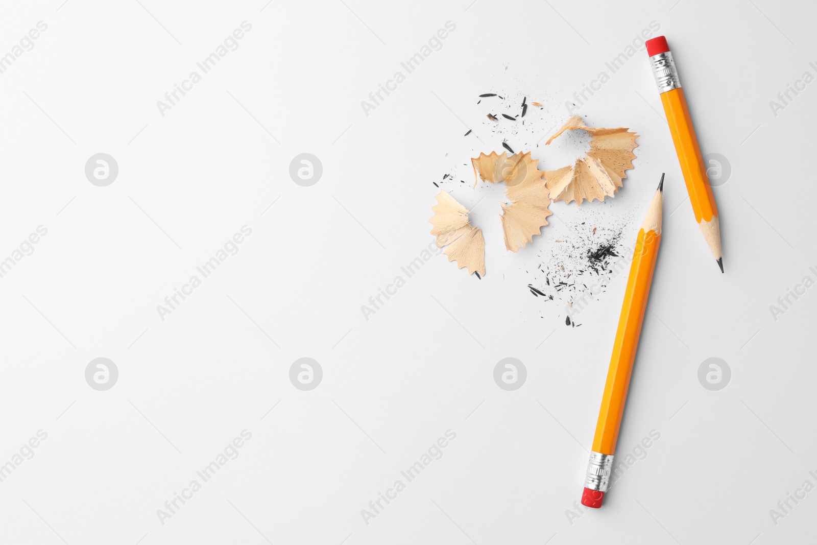 Photo of Graphite pencils and shavings on white background, flat lay. Space for text