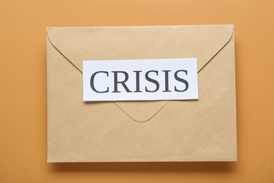 Photo of Envelope with word Crisis on brown background, top view